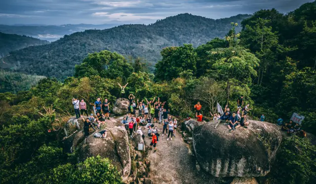 Drone shot of group on rocky boulders with forest valley