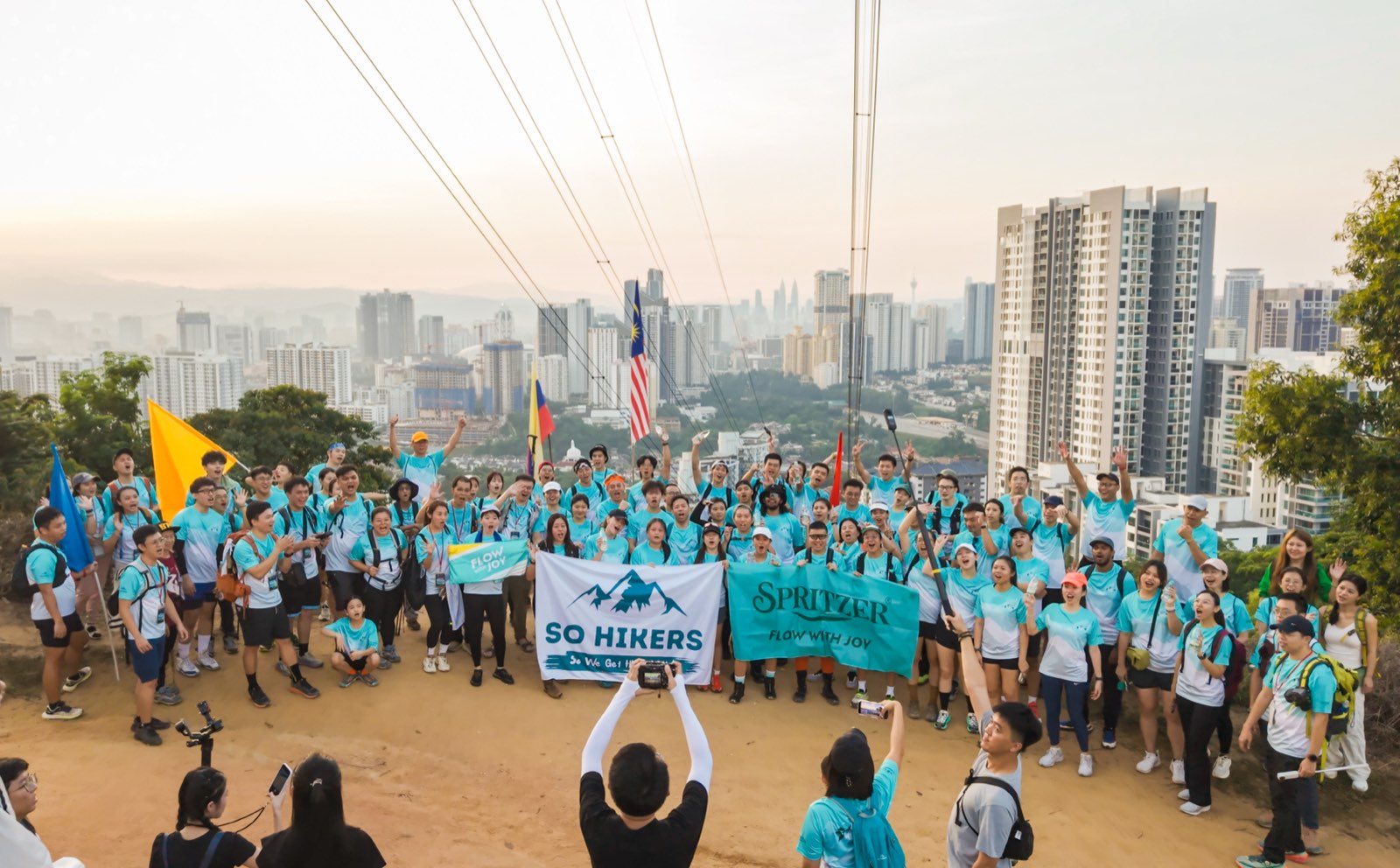 So Hikers x Spritzer group at the summit with KL city skyline and Malaysian flag