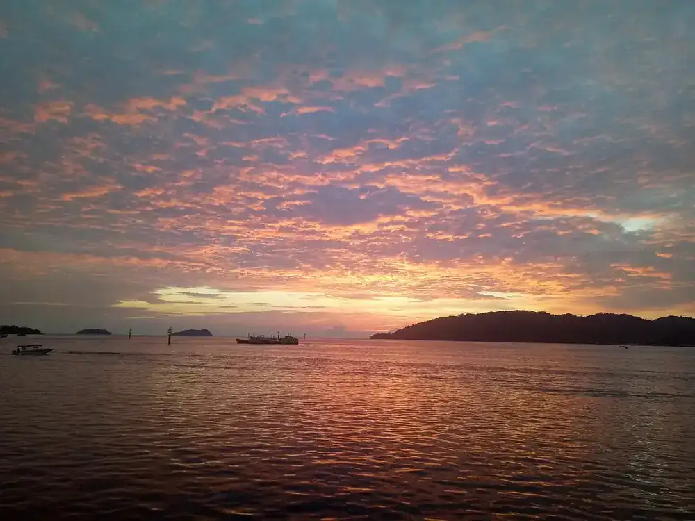 Orange and pink sunset clouds over the sea off Kota Kinabalu, islands on the horizon